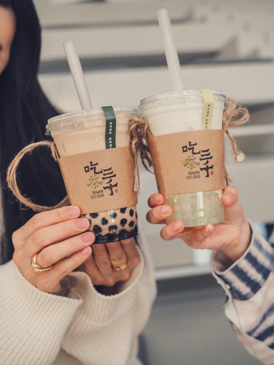 Two people holding bubble tea cups together, showcasing different flavors in plastic cups.